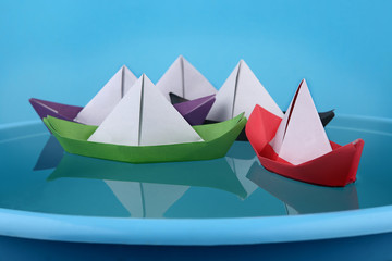 Paper boats game. Origami paper ships sailing on blue water surface.