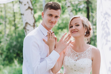 Beauty bride and handsome groom are wearing rings each other. Wedding couple on the marriage ceremony. Beautiful model girl in white dress. Man in suit. Female and male portrait. Wedding rings.