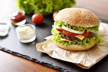 Fresh, delicious burger or cheeseburger with sauces and fresh ingredients. Hamburger on a slate plate.