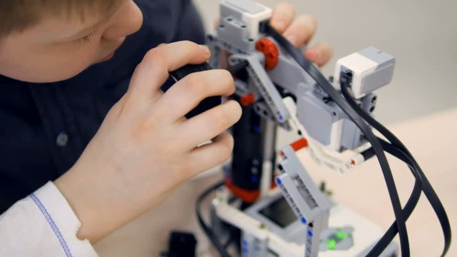 School boy at engineering classroom making robot. Robotechnics education. 4K.