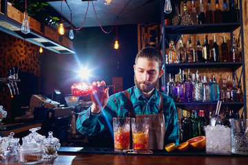 The bartender laughs making a cocktail at the bar.