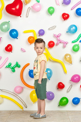 Obraz na płótnie Canvas boy on a white background with colorful balloons. boy in a tank top and shorts on a white background with balloons in the shape of a heart