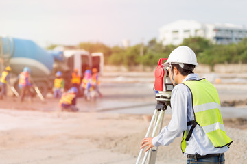 Asian Land surveyor and Asian civil engineer working with his equipment.