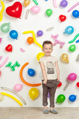 Fototapeta na wymiar boy on a white background with colorful balloons. boy in a tank top and shorts on a white background with balloons in the shape of a heart