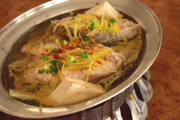 steamed grouper with ginger, tofu and chinese soy sauce served on hot pot.
