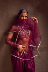 Eastern beautiful brunette .belly-dancer woman in afghani pants, purdah and adornment.