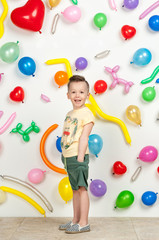 Fototapeta premium boy on a white background with colorful balloons. boy in a tank top and shorts on a white background with balloons in the shape of a heart