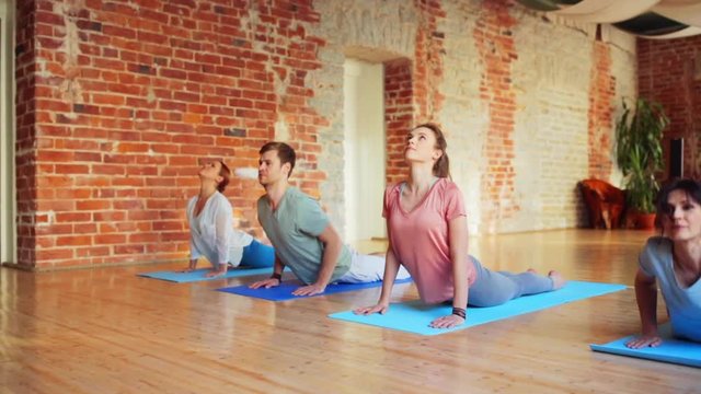 group of people making yoga exercises in gym