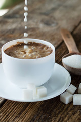 cup of coffee with milk and sugar spoon on the table