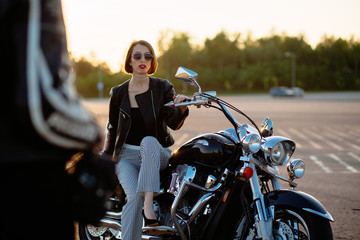 Fototapeta na wymiar Attractive woman biker posing near her motorcycle.