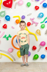 Fototapeta premium boy on a white background with colorful balloons. boy in a tank top and shorts on a white background with balloons in the shape of a heart