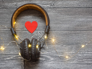 the heart next to the headphones. symbolizes the love of music. on wooden grey background