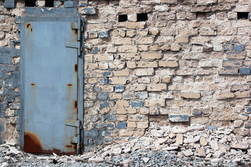 Rusty metal door in old destroyed brick wall