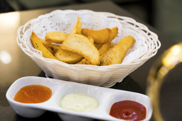 French fries in a cute basket with dipping sauces beside.
