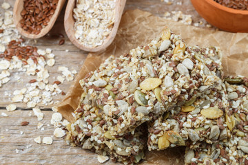 Healthy snack - crispy cereal cookies on old wooden table and ingredients: oat flakes, flax seed, pumpkin, sunflower, sesame. Diet crispy crackers. Selective focus