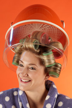 Eine Frau mit Lockenwickler im Haar unter der Trockenhaube