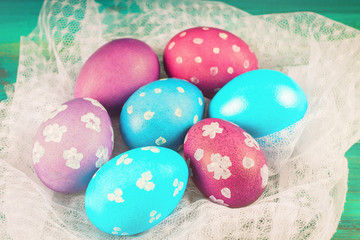 Fototapeta na wymiar Violet and blue Easter eggs on white fabric. Blue wooden background. Happy easter.