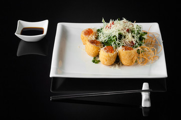 sushi in a white plate with sauce pot and chopsticks on a black background with reflection 