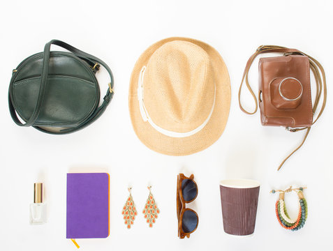 Holiday/travel background. Green cross bag, straw hat, retro brown sunglasses, retro camera, hippie bracelet and earrings, violet noutbook, coffee cup. Flat lay, top view. © Elena