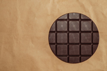 Bar of Round dark chocolate on old brown wrinkled paper. Pie chart concept