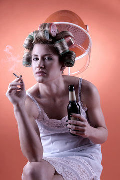a single housewife with a smoking cigarette and a bottle of beer in her hands