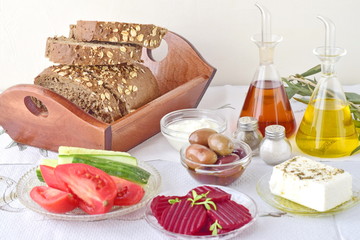 Greek food, mezedes. Jars with olive oil and vine vinegar, olives,feta, tzatziki, dark bread, raki, beetroot, fresh cucumber and tomato on a white background. Healthy eating concept. Healthy food.