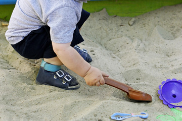 The kid plays in the sandbox.