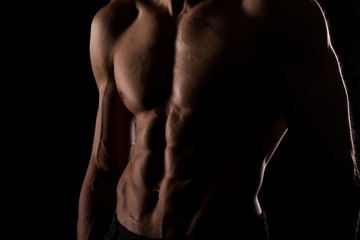 Muscular and defined six pack abs on handsome male model posing on black background