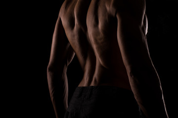 Male fitness model, bodybuilder back pose on black background