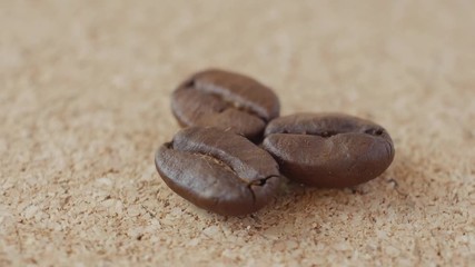 Three grains of coffee close-up on brown background. Rotation view.