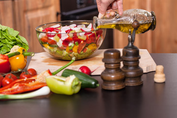 Making a fresh vegetables salad - pouring the oil