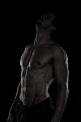 Fototapeta na wymiar Muscular and defined six pack abs on handsome male model posing on black background