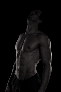 Muscular and defined six pack abs on handsome male model posing on black background