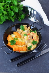 Chicken fillet with mushrooms in a creamy souce and fried sweet potato in a black metal bowl on a grey abstract background. Healthy eating concept.