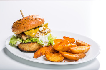 Tasty chicken burger with wedges, on a white plate