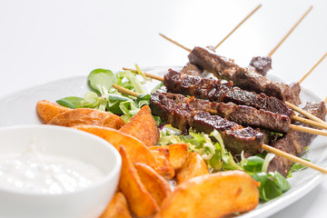 Lamb skewers on salad with wedges potatoes