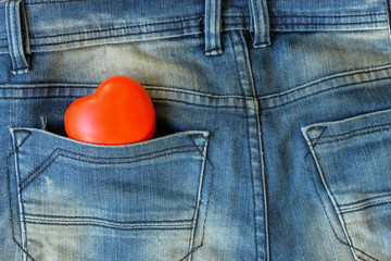  red heart in the pocket of blue jeans close up.