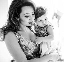 Black and white picture of beautiful mother holding her little daughter on the arms