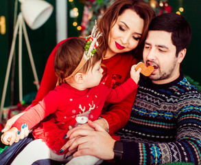 Girl in red dress reaches out hand with cookie to her father