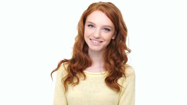 Beautiful young woman with long red curly hair looking at camera isolated over white