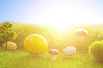 Decorated easter eggs in green grass on sunset sky background.