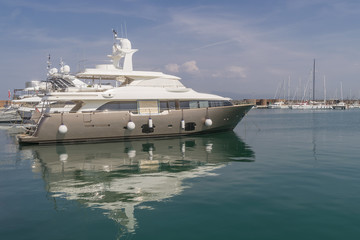 Fototapeta na wymiar A luxury yacht is reflected in the sea water of the marina of Marina di Pisa, Tuscany, Italy, on a sunny day
