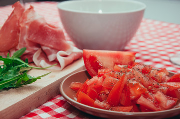 Sliced tomatoes  and prosciutto on table