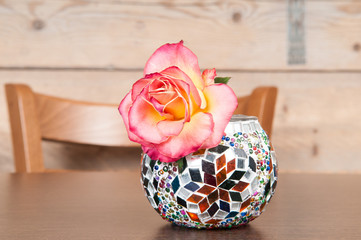 single rose flower in ornamental vase on the table