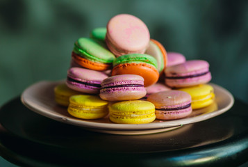 Violet and yellow macaroons served on pink plate