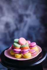 Violet and yellow macaroons served on pink plate stand on bar chair