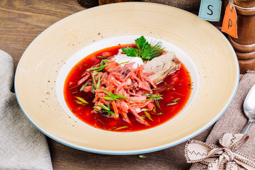Ukrainian and Russian traditional beetroot soup - borscht in bowl with sour cream and herbs