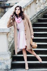 Obraz premium Woman in pink dress looks far away posing on old stone stairs outside