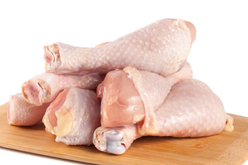 raw chicken drumsticks on a wooden cutting boardn white background