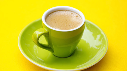 green cup with coffee on yellow table